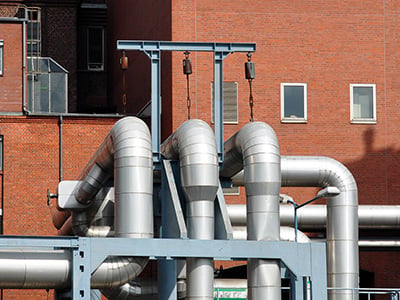 Industrielle Rohrleitungen mit Manometer als Beispiel für die Weitergabe von Abwärme an ein Nachbarunternehmen
